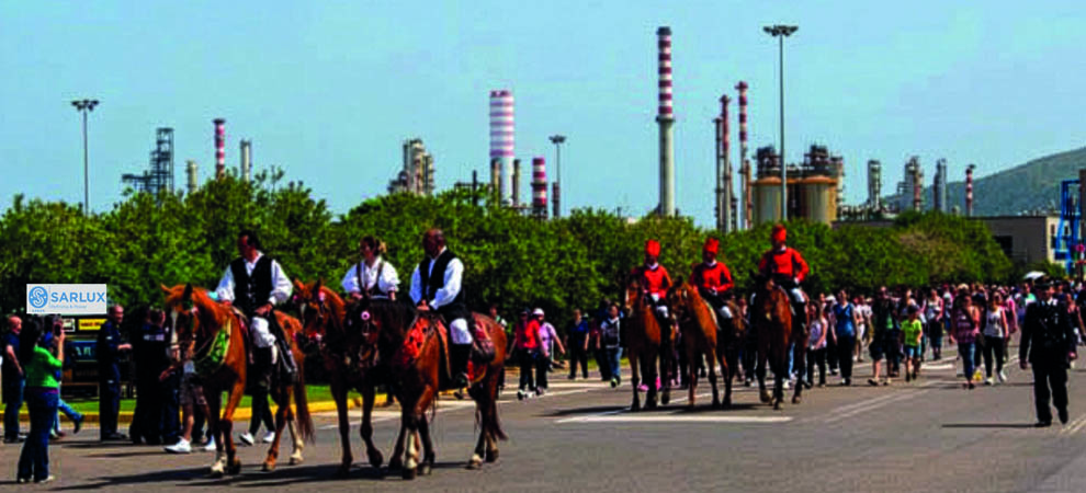 Ogni 1° maggio, il passaggio di Sant’Efisio davanti alla raffineria Sarlux coincide con la Festa del Lavoro e rappresenta un momento simbolico per i lavoratori dello stabilimento. La processione si ferma davanti agli impianti, accompagnata dal saluto delle sirene e dai giochi d’acqua organizzati dal personale in turno: un gesto che testimonia un legame radicato nel territorio.